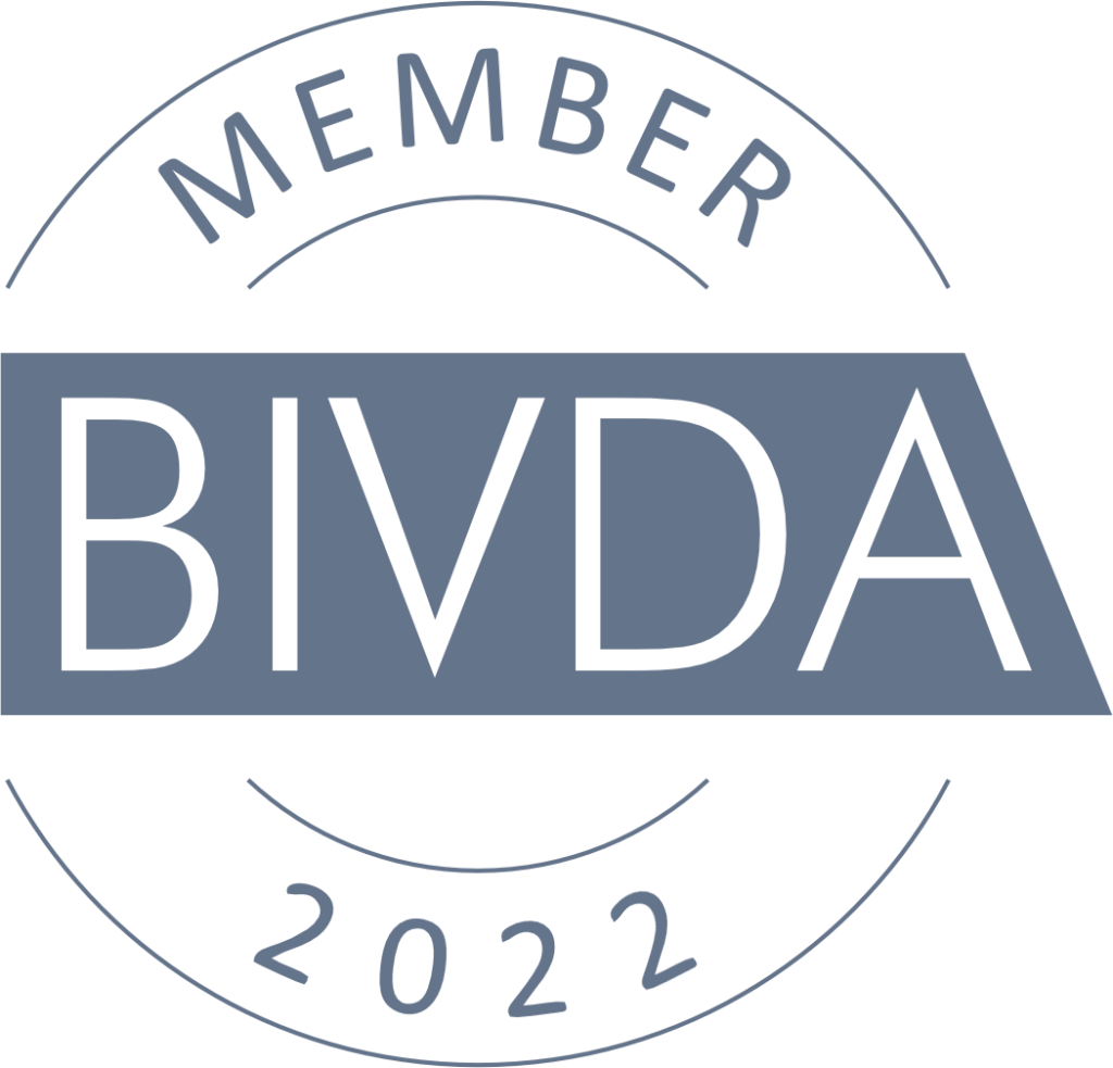 The BIVDA Member badge for 2022 features a circular seal design rendered in a muted slate-blue. In the center, a solid rectangular block with a slanted right edge contains the acronym "BIVDA" in large, white, sans-serif capital letters. The word "MEMBER" arches along the top of the circle in a matching blue font, while the year "2022" curves along the bottom. Thin circular lines frame the text at the top and bottom, completing the professional, official look of the membership emblem.